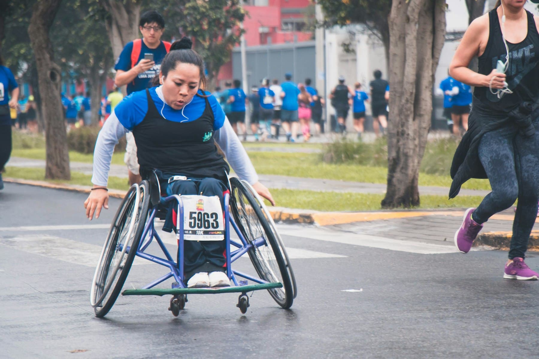 A woman in a racing wheelchair taking part in a community fun run